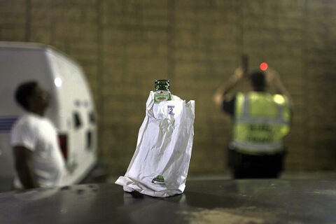 Beer bottle in paper bag with DUI stop in background