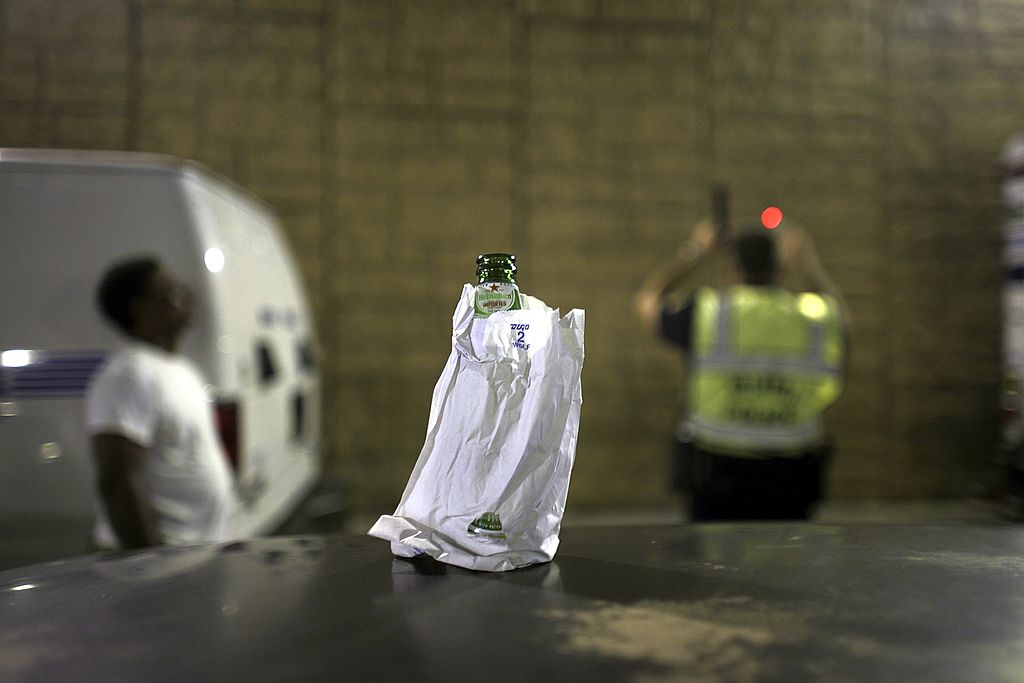 Beer bottle in paper bag with DUI stop in background