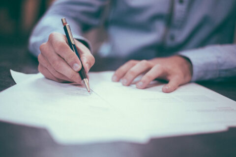 Close-up of hands signing a document