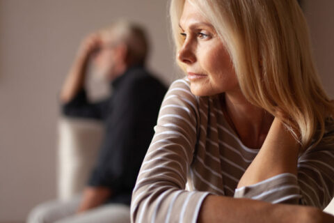 Woman staring sadly in the distance with man in background