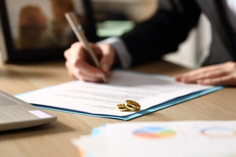Divorce attorney signing documents with two wedding rings on top