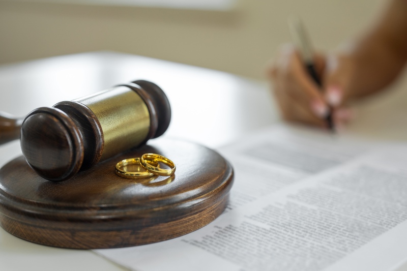 Wedding rings and a gavel with a person signing a contract in Ogden, UT
