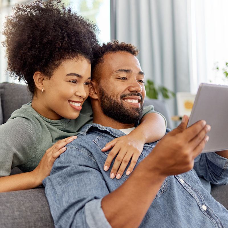 A couple relaxing on a couch reviewing information about Ogden, Utah's Domestic Partnership Law.