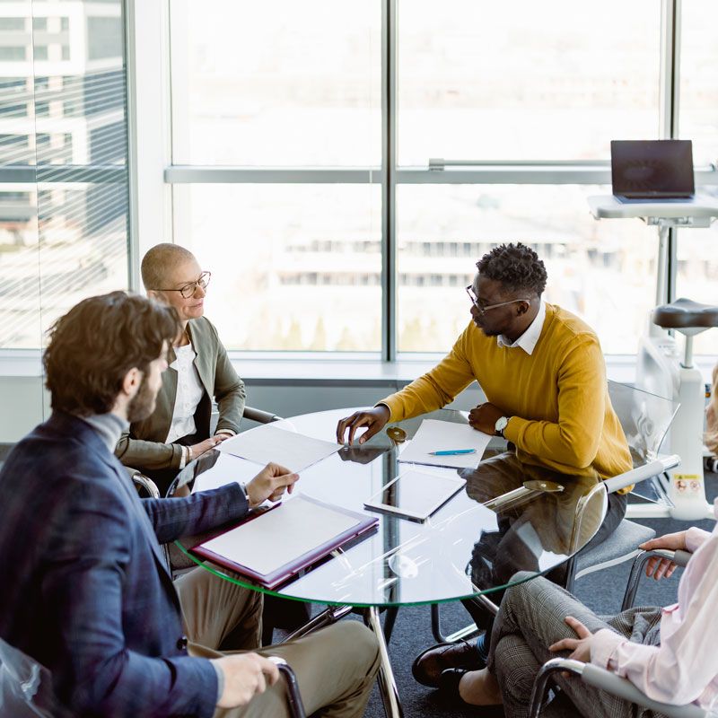 Group meeting around a glass table in an office discussing immigration in Ogden, Utah
