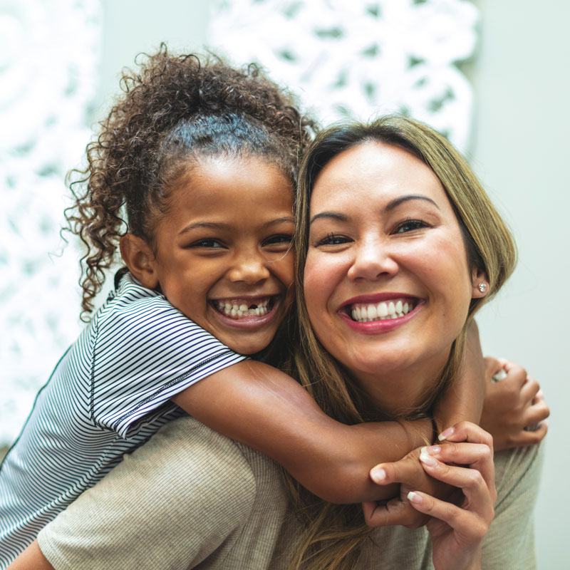 Child hugging an adult from behind while standing together in Ogden, Utah