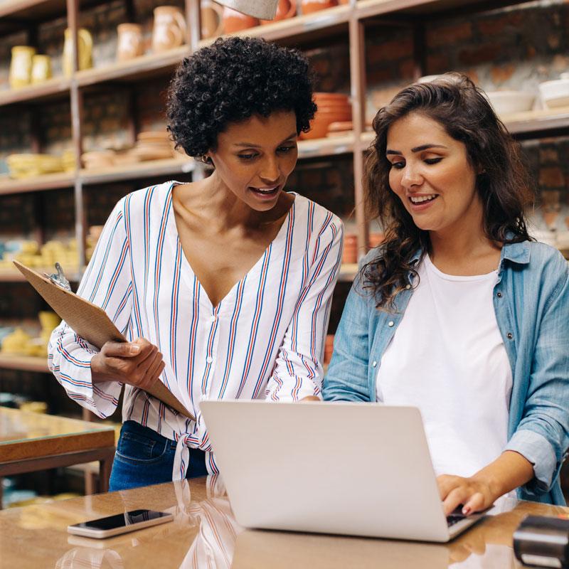 Two people reviewing inventory on a laptop in a shop in Ogden, Utah