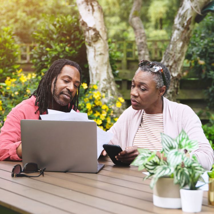 Adults reviewing estate documents together on a laptop at an outdoor table in Ogden, UT