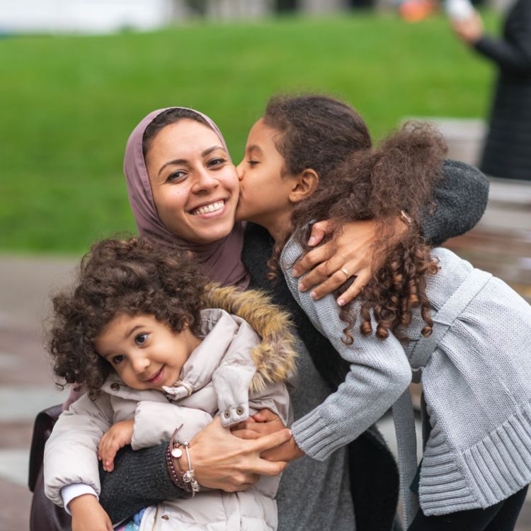 An adult sitting with two children during a relaxed moment outdoors on a bench in Ogden, UT
