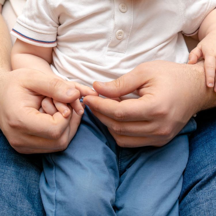 A parent gently holding the hands of a child on a lap in Ogden, UT